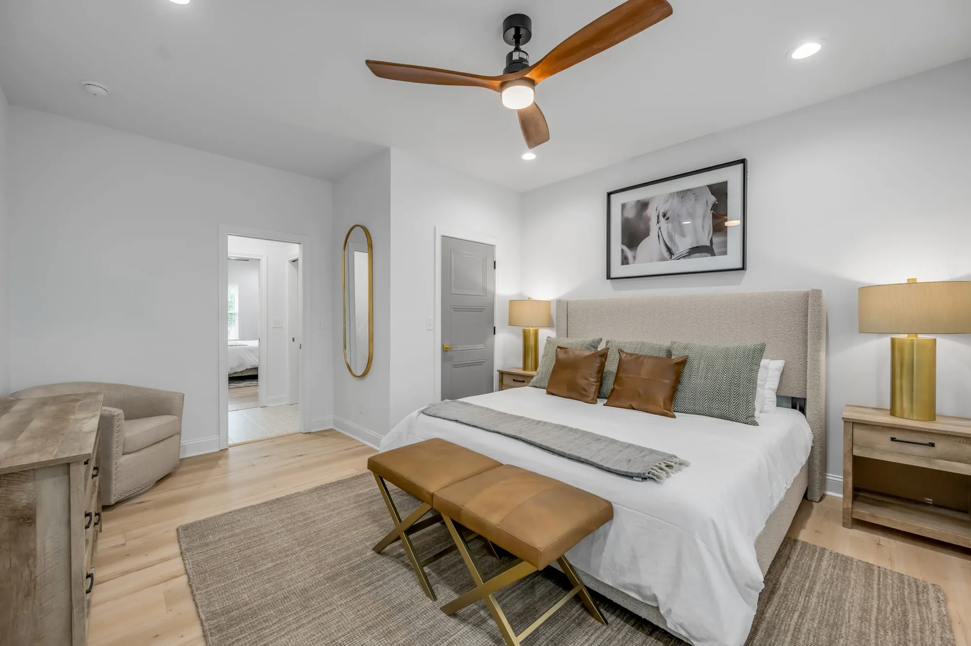 Second bedroom at 341 Sherman with a made bed, a sitting chair, and an oval mirror