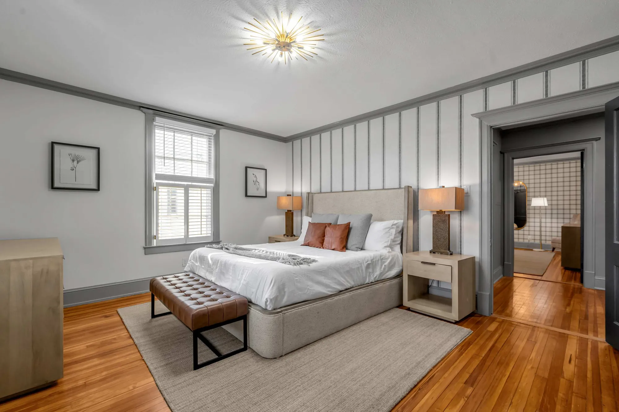 Primary bedroom at Adair with a made bed, a leather bench, and a fireplace